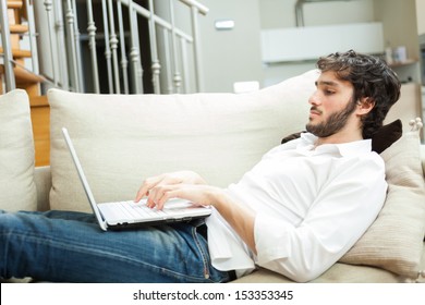 Man Using A Laptop While Relaxing On The Couch