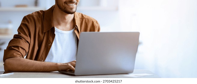 Man Using Laptop While Sitting at Table in Bright Room During Daytime Hours