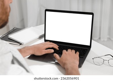 Man using laptop at white table indoors, closeup