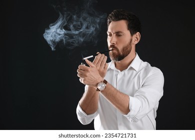 Man using long cigarette holder for smoking on black background, space for text