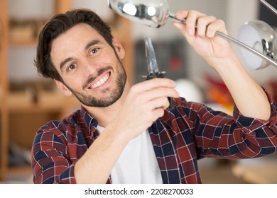 Man Using Long Nosed Pliers On A Standard Lamp