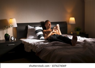 Man Using Mobile Phone In Bed