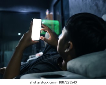 Man Using A Mobile Phone On The Sofa In House At Night With A White Screen And Clipping Path.