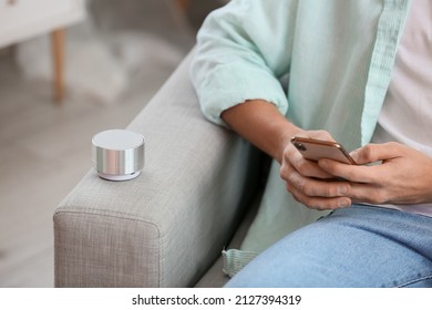 Man Using Mobile Phone On Sofa With Wireless Portable Speaker, Closeup