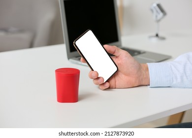 Man Using Mobile Phone On Table With Wireless Portable Speaker, Closeup