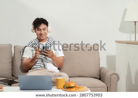 Man are using a mobile phone playing social media and laptop wifi connection sitting on sofa, home office workplace lifestyle people.