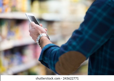 Man Using Mobile Phone While Shopping In Shopping Store