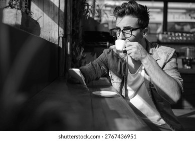 Man using mobile phone while having cup of tea in cafÃ©