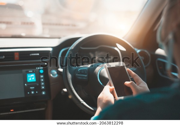 Man\
using mobile smart phone inside a car. Driver hand holding blank\
black screen smartphone, searching address and pin location via map\
navigator application, transportation\
technology