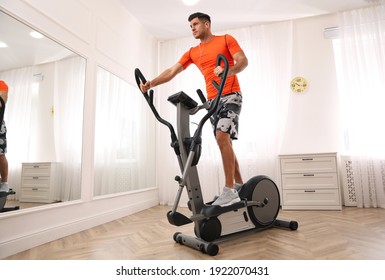 Man Using Modern Elliptical Machine At Home