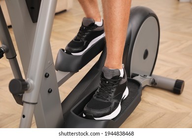 Man using modern elliptical machine indoors, closeup