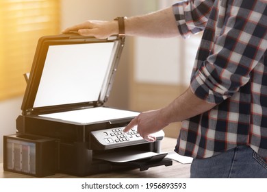 Man Using Modern Multifunction Printer In Office, Closeup