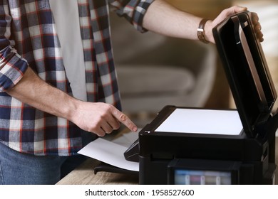 Man Using Modern Multifunction Printer In Office, Closeup