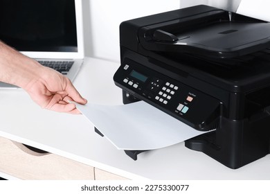 Man using modern printer at white desk in office, closeup