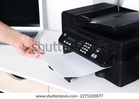 Man using modern printer at white desk in office, closeup