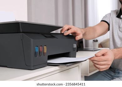 Man using modern printer at workplace indoors, closeup