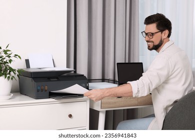 Man using modern printer at workplace indoors