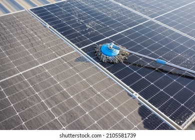 Man Using A Mop And Water To Clean The Solar Panels That Are Dirty With Dust And Birds' Droppings To Improve The Efficiency Of Solar Energy Storage.