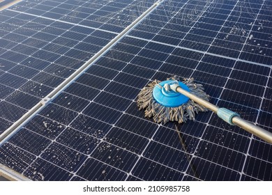 Man Using A Mop And Water To Clean The Solar Panels That Are Dirty With Dust And Birds' Droppings To Improve The Efficiency Of Solar Energy Storage.