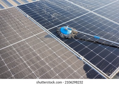 Man Using A Mop And Water To Clean The Solar Panels That Are Dirty With Dust And Birds' Droppings To Improve The Efficiency Of Solar Energy Storage.