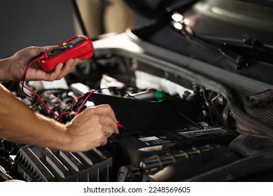 Man using multimeter to measure the voltage of the batteries. Mechanic doing car inspection, he is testing car battery with tester. Check battery voltage with electric multimeter.