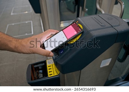 Man using NFC contactless payment near electronic validator, paying for public transport with mobile phone