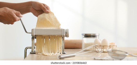 Man using pasta machine in kitchen