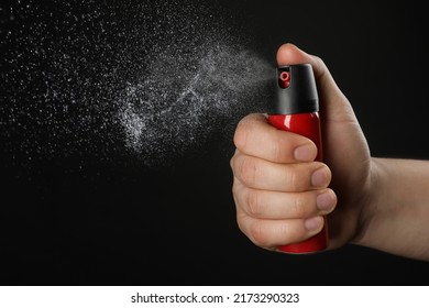 Man using pepper spray on black background, closeup