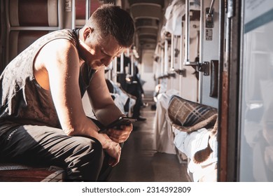 a man using a phone in the aisle of a second-class carriage of a high-speed train waiting for his stop, the background is blurred