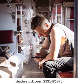 a man using a phone in the aisle of a second-class carriage of a high-speed train waiting for his stop, the background is blurred
