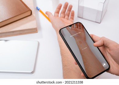 Man using a phone app to identify a red spot on his hand. Identifying skin disease with artificial intelligence available for everybody.