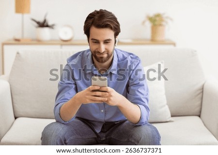 Man Using Phone Browsing Internet Sitting On Couch At Home