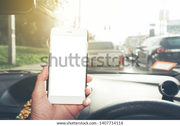 man using phone in car, GPS navigation , white\
screen frame on smartphone in hand with blur image of traffic jam\
as background