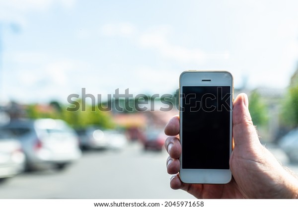 Man using phone in car, GPS\
navigation ,blank space frame on smartphone in hand with blur image\
of traffic jam as background.Man using cell phone while\
driving.