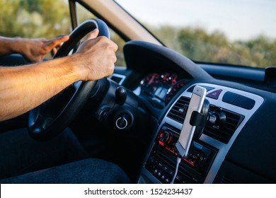 Man using phone with hand while driving a car