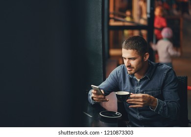 man using phone inside a restaurant while drinking cofee - Powered by Shutterstock