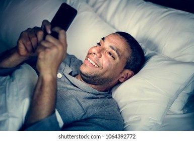 Man Using Phone On A Bed