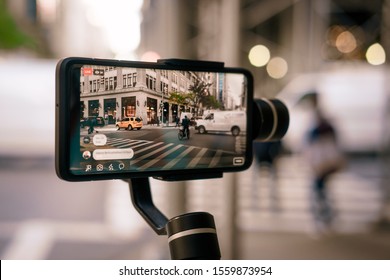 Man using phone with stabilizer and taking pictures and live video in New York city. Vlog, video blogging, street photography concept. 
