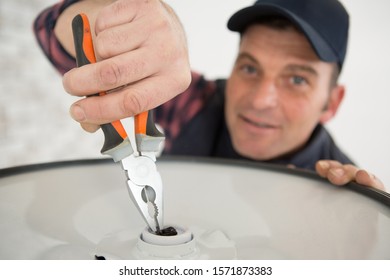 Man Using Pliers On A Metal Disc