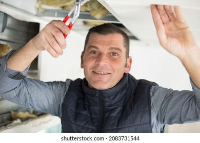 Man Using Pliers On Overhead Job