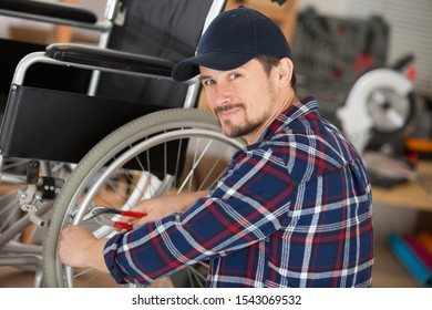 Man Using Pliers To Service The Brakes On A Wheelchair