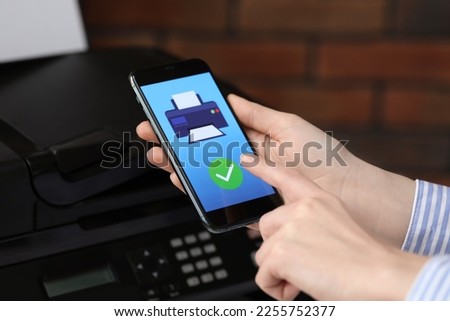 Man using printer management application on mobile phone indoors, closeup. Image on device screen.