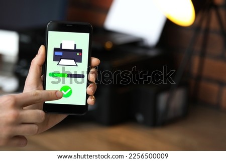 Man using printer management application on mobile phone indoors, closeup and space for text