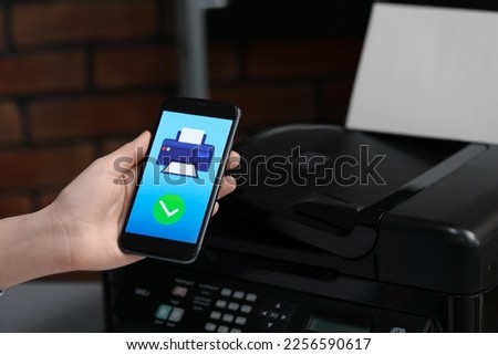 Man using printer management application on mobile phone indoors, closeup. Image on device screen.