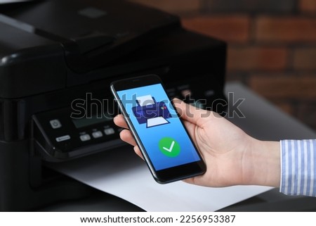 Man using printer management application on mobile phone indoors, closeup. Image on device screen.
