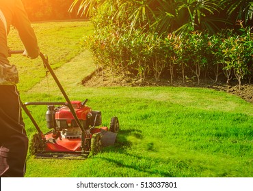 Man Using  Red Lawnmower Cutting Bright Green Grass In Football Fields Backyard Gardening Care Service Landscaping For The Background Lawnmower On Grass Equipment Mowing Gardener Care Work Tool.