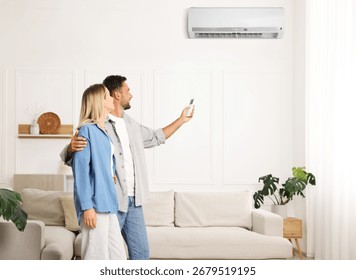Man using remote to control air conditioner and hugging his girlfriend at home