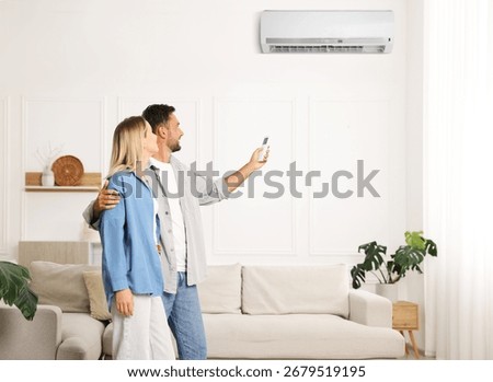 Man using remote to control air conditioner and hugging his girlfriend at home
