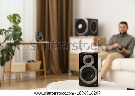 Man using remote to control modern audio speaker system in bright room