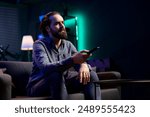 Man using remote control to switch channels, gripped by suspenseful films shown on television screen. Person mindlessly scrolling through streaming content, stopping after seeing interesting movie